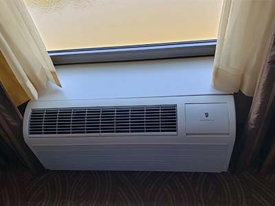 Picture of through-the-wall AC unit installed below a window, similar to how they are in a hotel room.