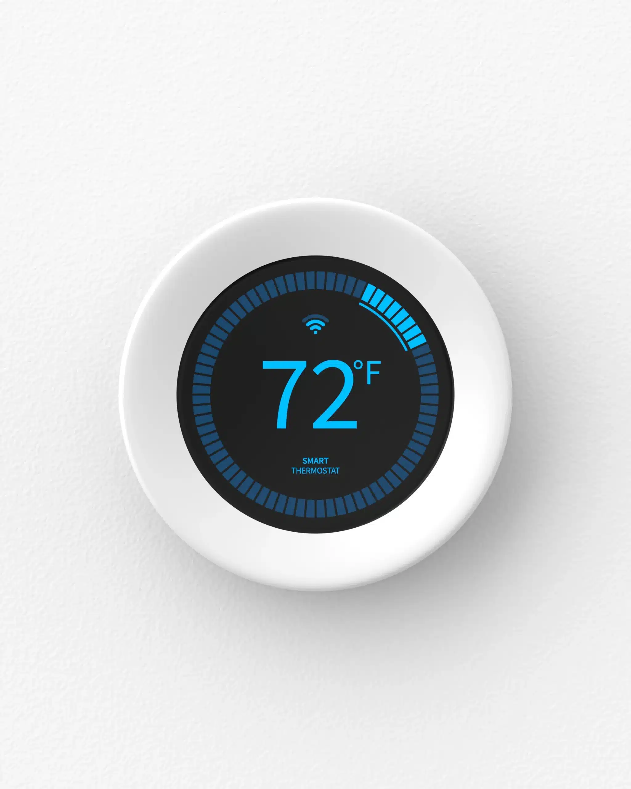 A round smart thermostat mounted on a white wall displays a temperature of 72°F on its digital screen.