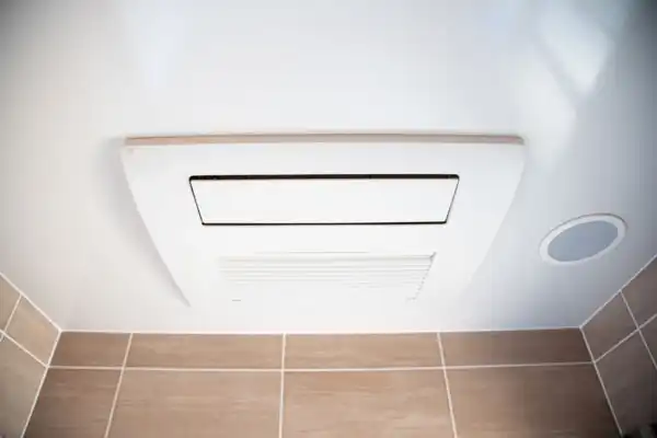 Ceiling-mounted bathroom exhaust fan with a vent, installed above tiled walls.